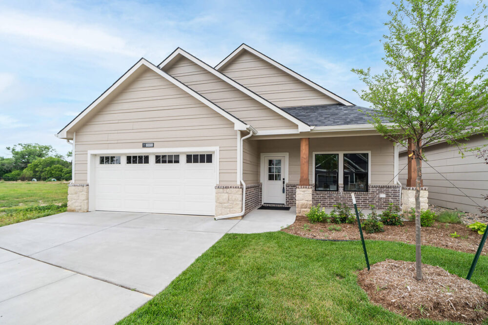 Neutral colored ranch patio home with beige brick. Two car garage.
