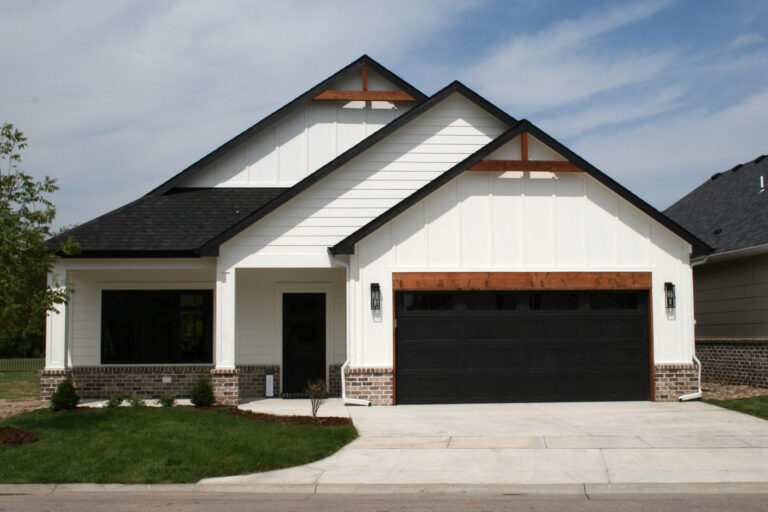 A white patio home with black and wood accents and neutral brick.