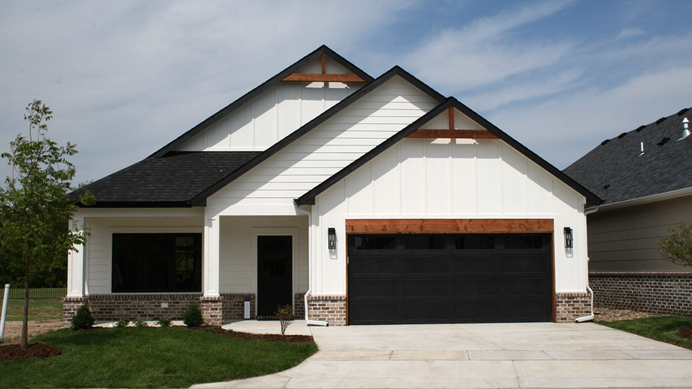 A white patio home with black and wood accents and neutral brick.